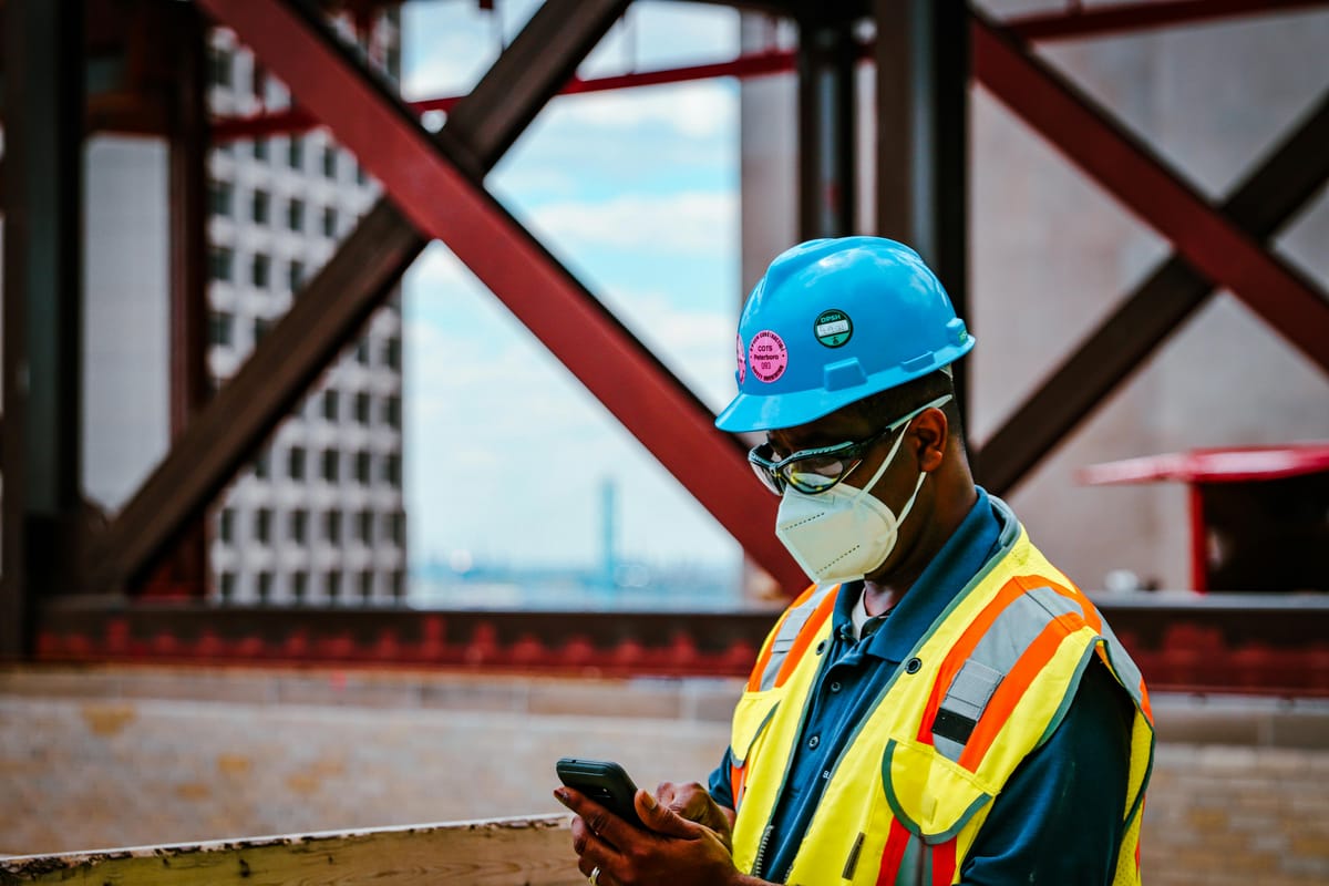 General worker wearing personal protective equipment (PPE) using a cellphone